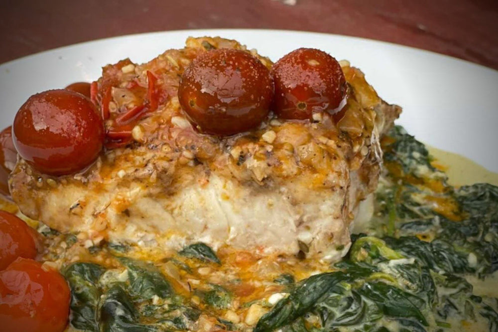 Parmesan crusted Catch Sitka Seafoods Lingcod over creamy spinach with tomatoes.  